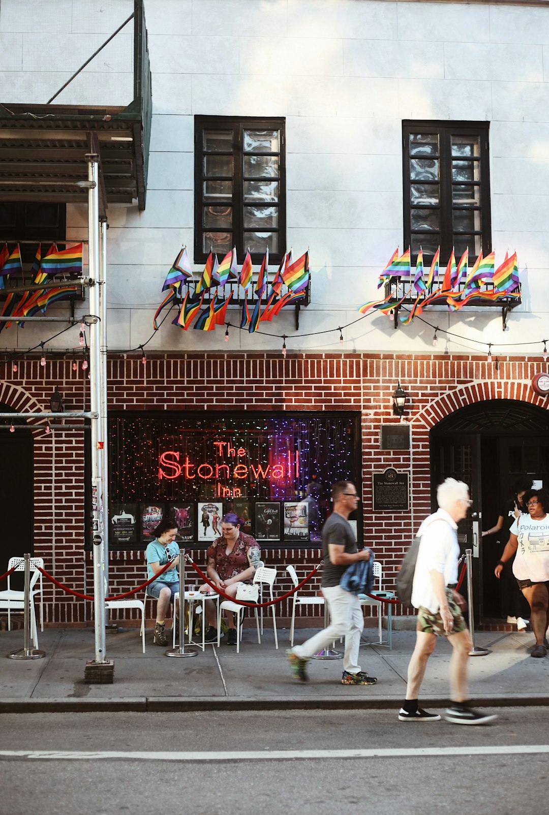 a group of people walking on a sidewalk in front of a restaurant a group of people walking on a sidewalk in front of a restaurant