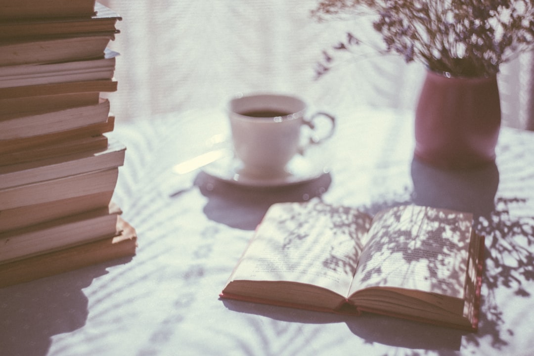 open book beside white ceramic teacup on saucer open book beside white ceramic teacup on saucer