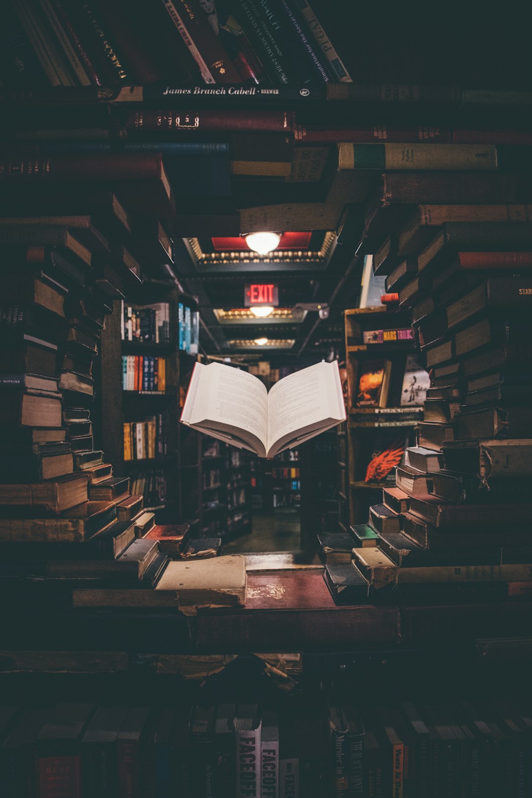 view of floating open book from stacked books in library view of floating open book from stacked books in library
